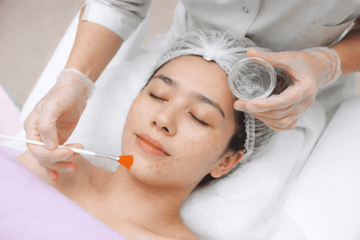 Woman receiving acne facial treatment with exfoliation at skincare clinic