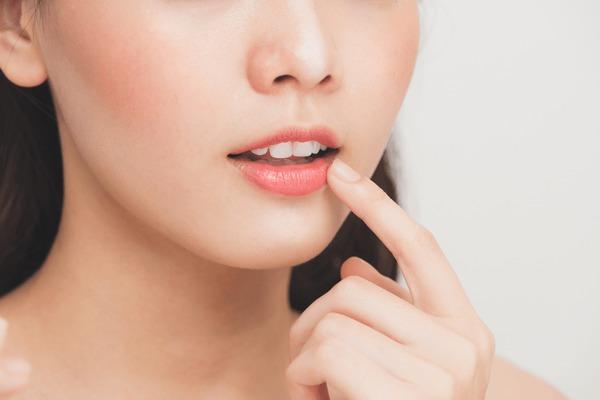 Close-up of woman gently touching her lips with a finger