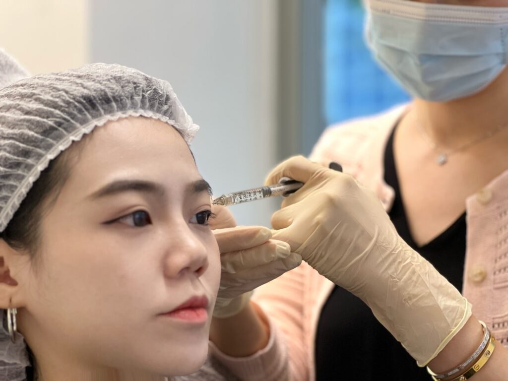injecting fillers in temple of asian woman