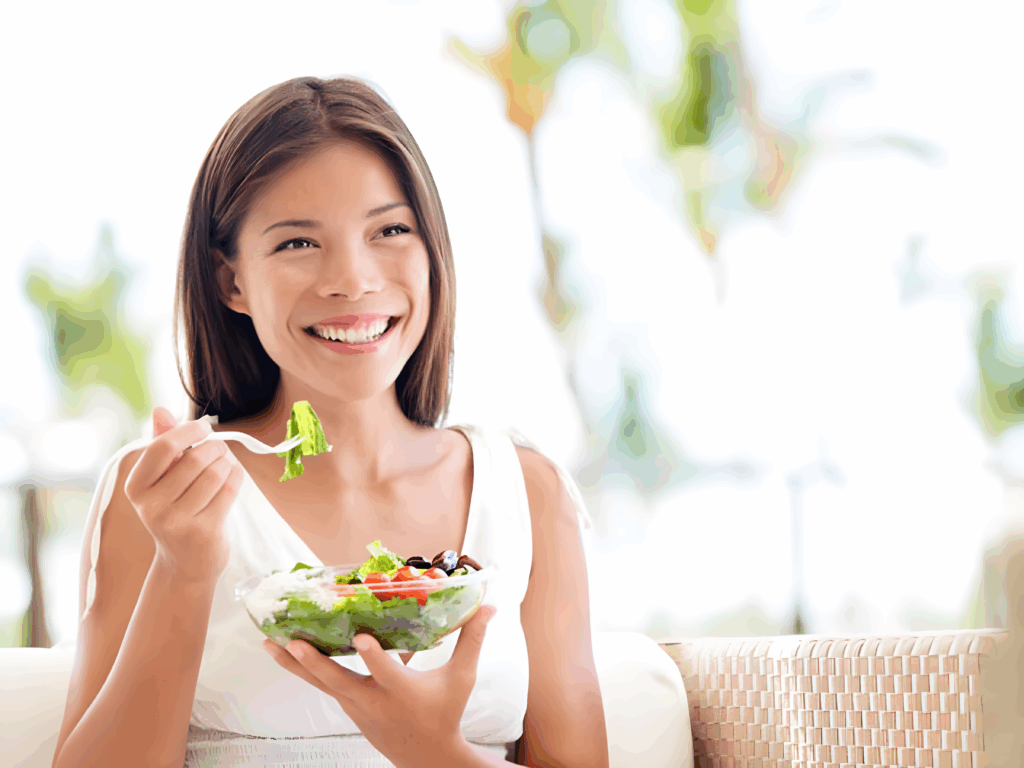 Smiling woman eating a fresh salad as part of a healthy lifestyle