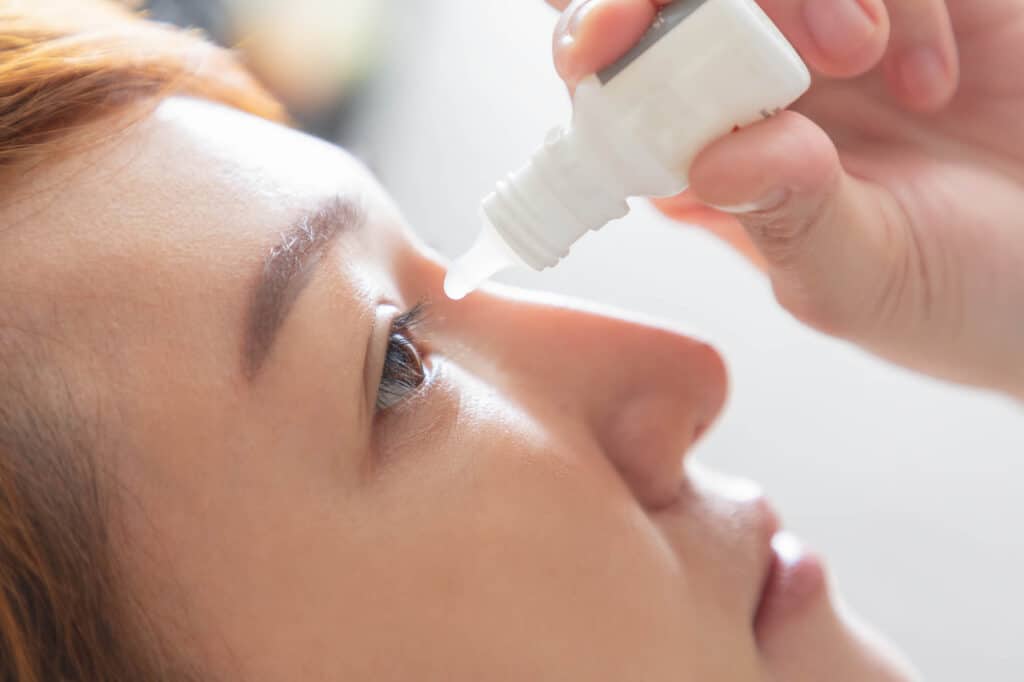 Closeup view of young asian woman applying eye drop. artificial tears.